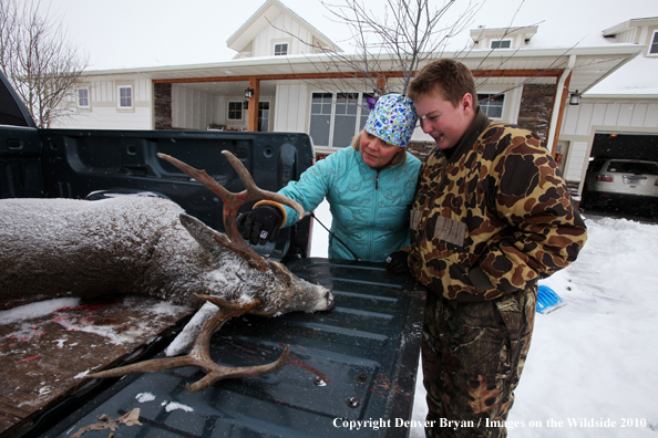 Son shows off his downed white-tail buck to mother