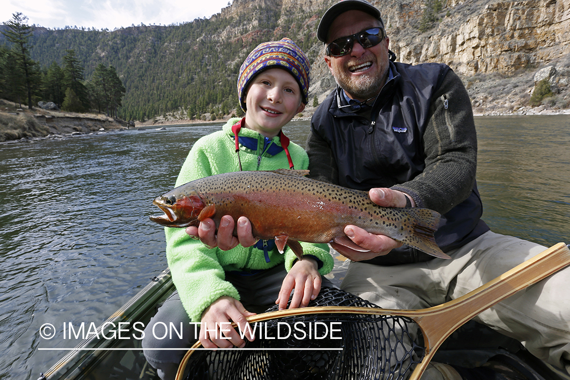 Father and son with Rainbow trout on river.