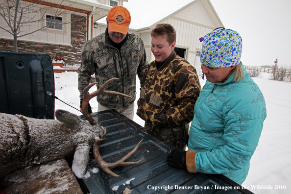 Son shows off his downed white-tail buck to mother