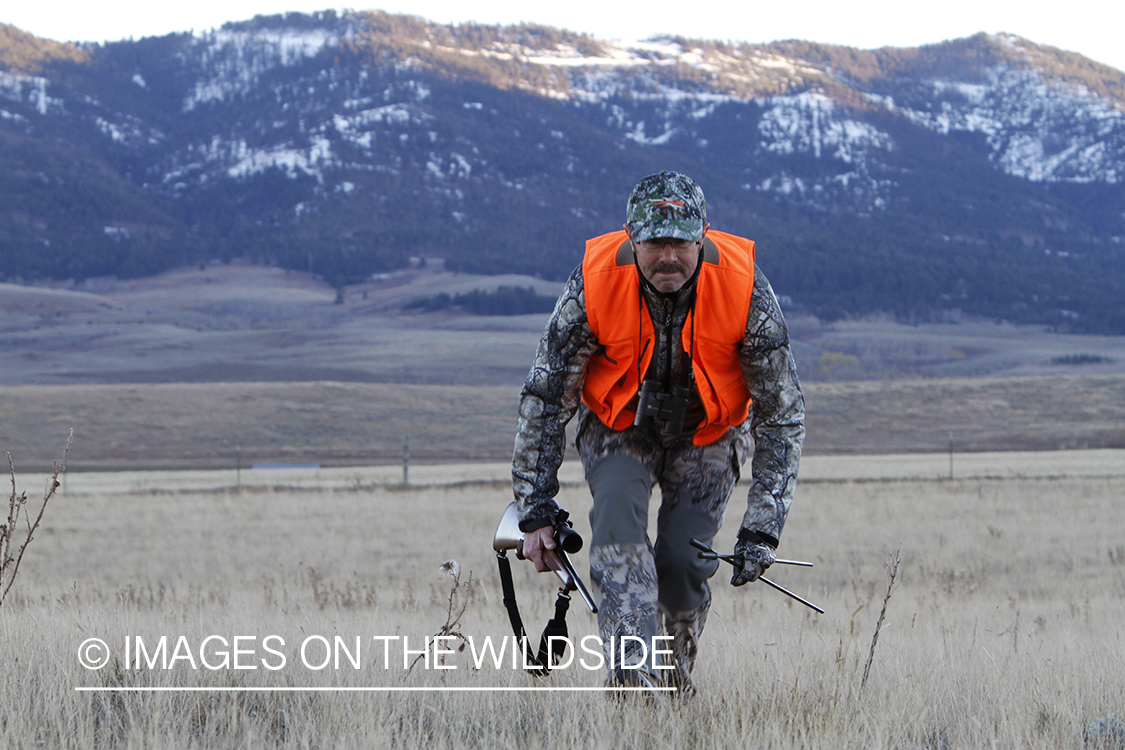 Big game hunter stalking game in field.