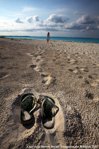 Woman walking beach to go flyfishing.                                