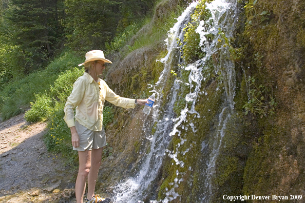 Lady filling water bottle.