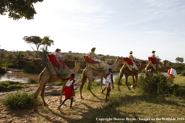 Family riding camels on african safari