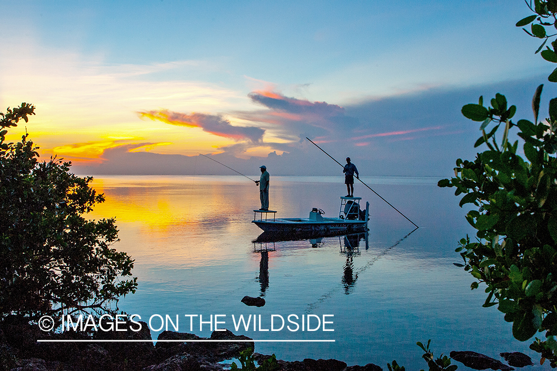 Flyfisherman with guide on flats boat at sunrise.