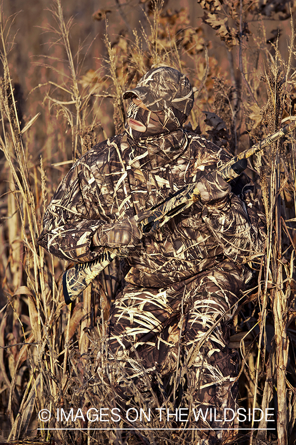 Waterfowl hunter camouflaged in wetlands.