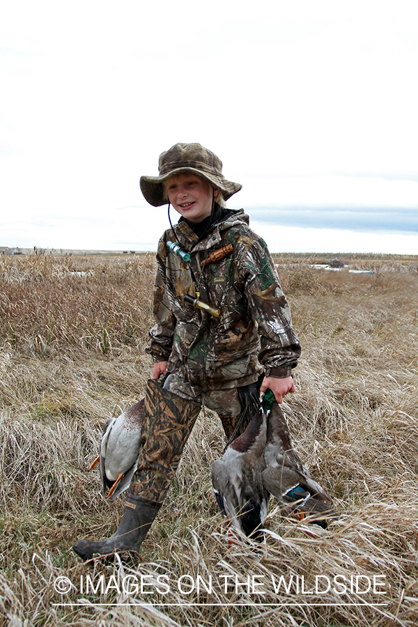 Father and son waterfowl hunters with bagged waterfowl.