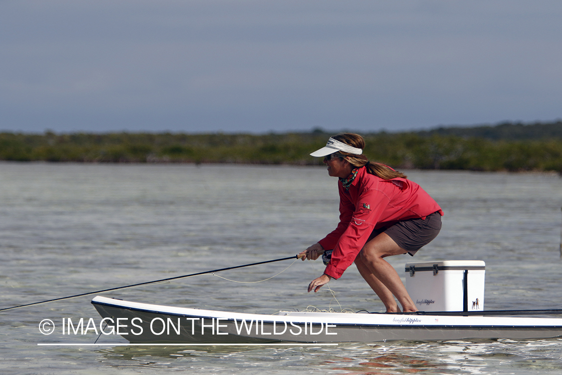 Saltwater flyfishing woman on stand up paddle board looking for fish.