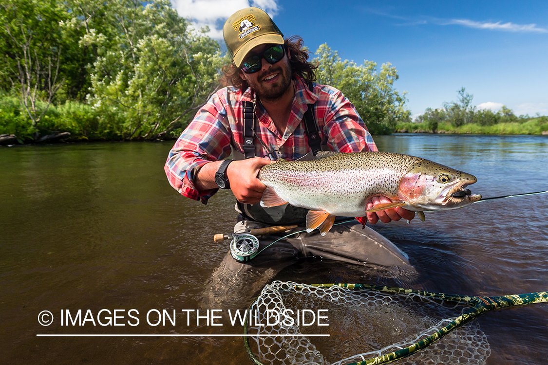 Flyfisherman with rainbow trout in Sedanka river in Kamchatka Peninsula, Russia.