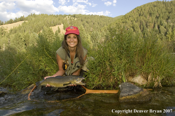 Woman flyfisher with large brown trout.