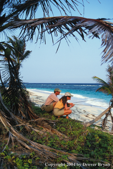 Saltwater flyfishing couple look for fish from beach.