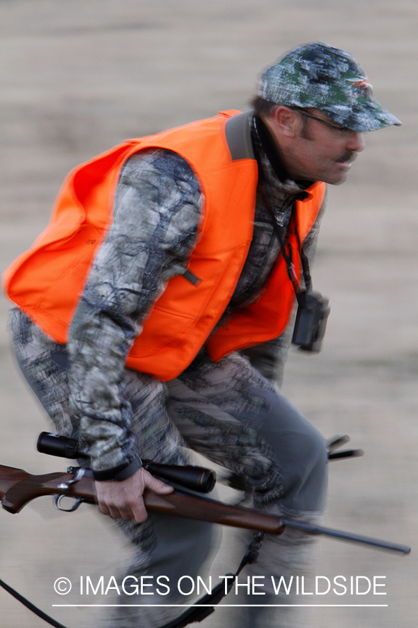 Big game hunter stalking game in field.