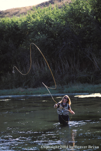 Woman flyfisher casting in river.