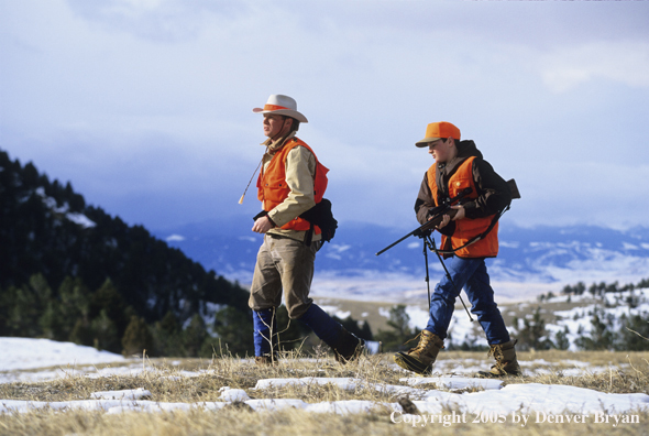 Father and son hunters big game hunting in a field in winter.