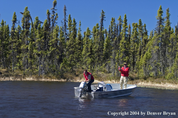 Flyfisherman, with guide, playing fish from boat.