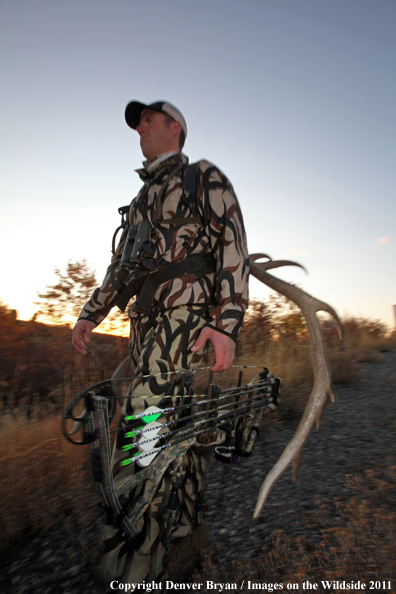 Bow hunter hiking with elk rack.  