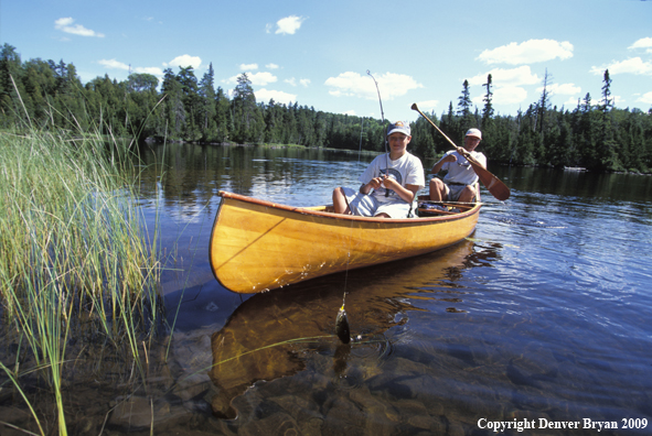 Father and son fishing from cedar canoe.