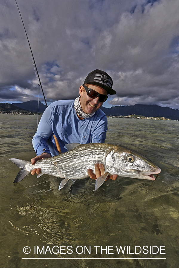 Saltwater flyfisherman with 13 lb bonefish, in Hawaii. (HDR)