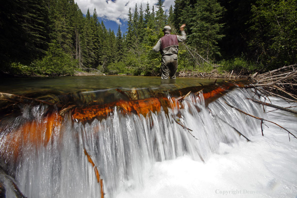 Flyfisherman standing above waterfall flyfishing