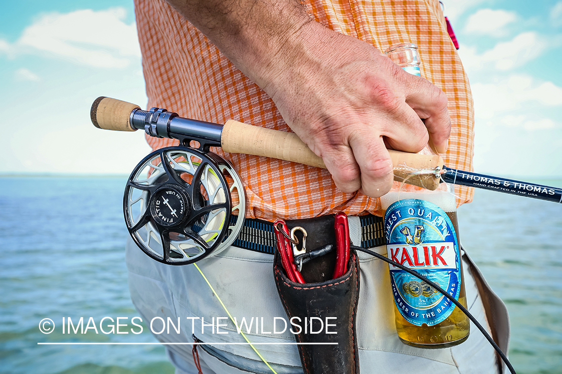 Flyfisherman with fly rod and Kalik beer.