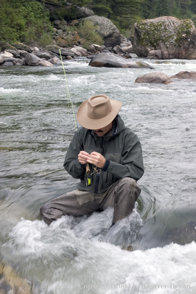 Flyfisherman rigging up to fish on stream.