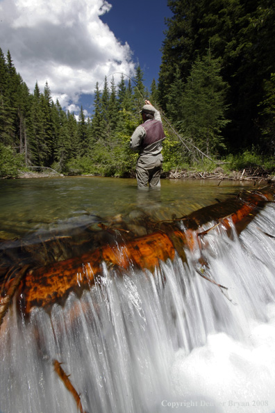 Flyfisherman standing above waterfall flyfishing