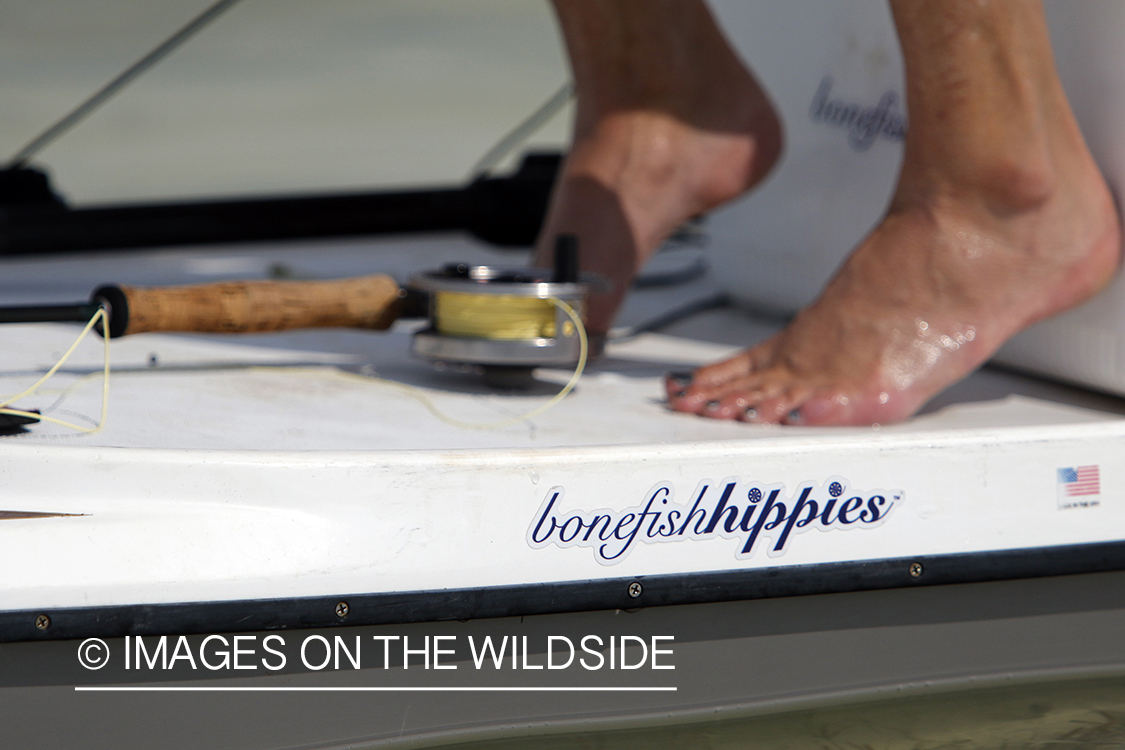 Saltwater flyfishing woman on paddle board with fishing rod.