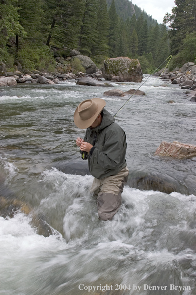 Flyfisherman rigging up to fish on stream.