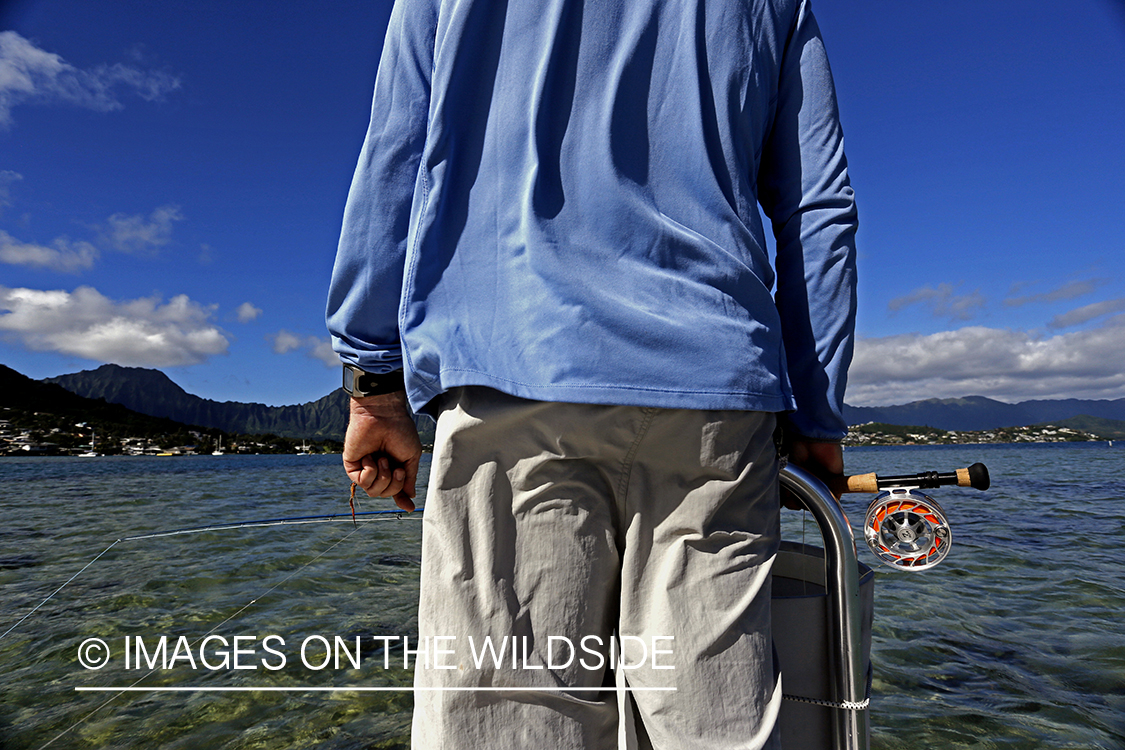 Saltwater flyfisherman fishing on flats boat, in Hawaii. 