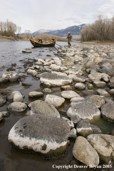 Flyfisherman walking toward boat on river.