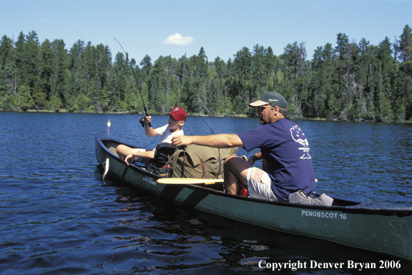 Father and son fishing from cedar canoe.  Small-mouth bass on line.