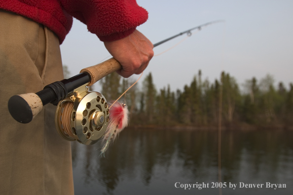 Flyfisherman holding rod, looking out from boat.