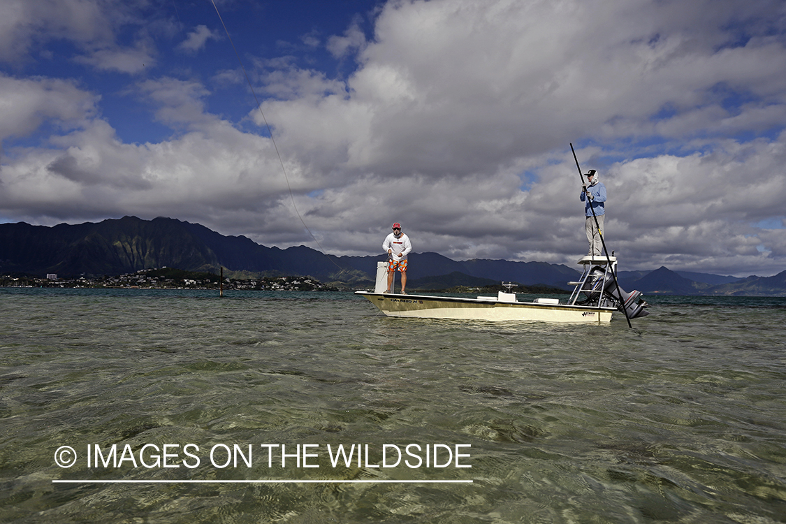 Saltwater flyfishermen fishing on flats boat, in Hawaii.