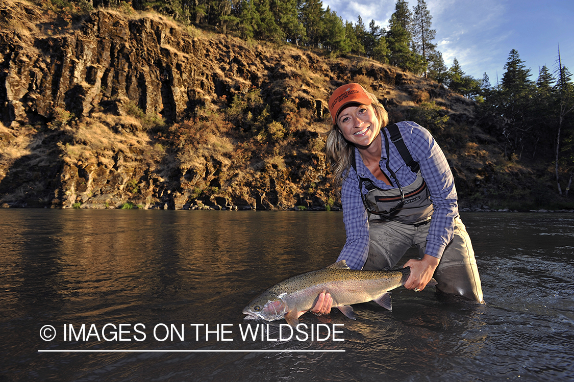 Woman flyfisher with steelhead catch. 