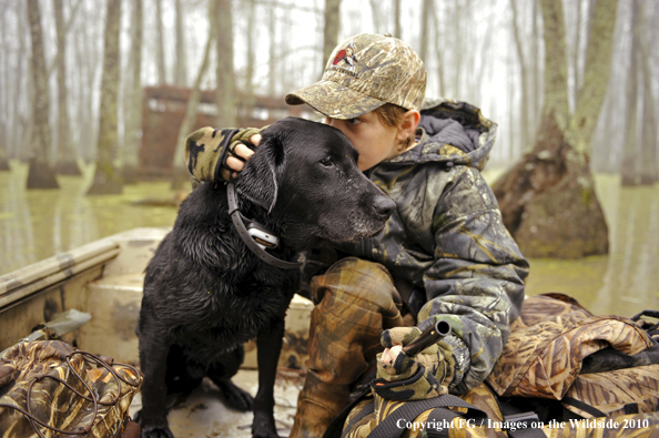 Waterfowl Hunting Kid with Fellow Black Labrador Retriever sitting in boat