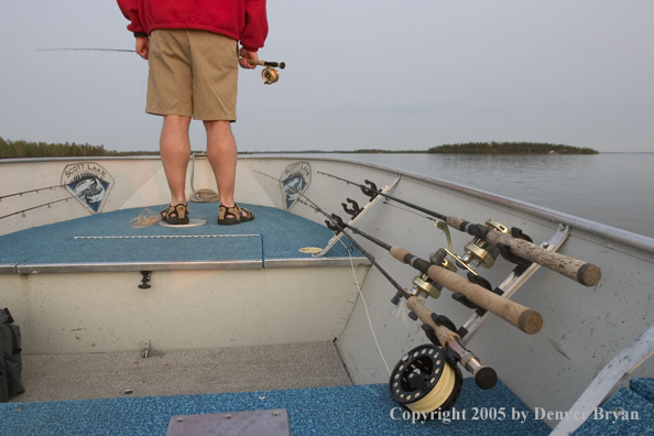 Flyfisherman holding rod, looking out from boat.