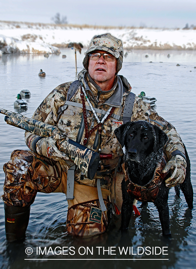 Waterfowl hunter and dog with decoys.