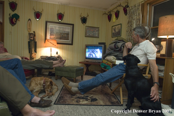 Upland game bird hunters lounging in living room with dogs.