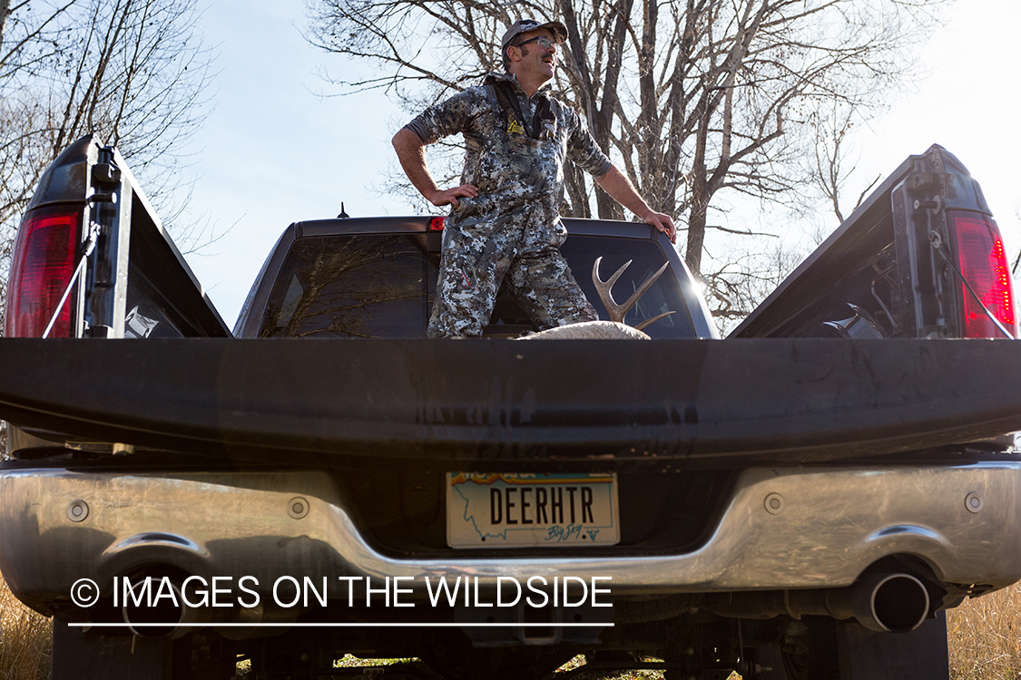 Exhausted bow hunter in truck with white-tailed deer.