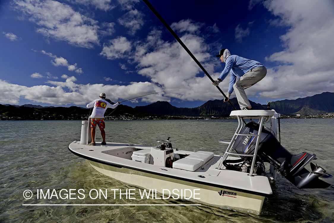 Saltwater flyfishermen fishing on flats boat, in Hawaii.