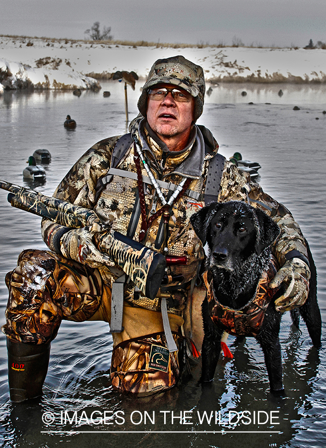 Waterfowl hunter and dog with decoys.