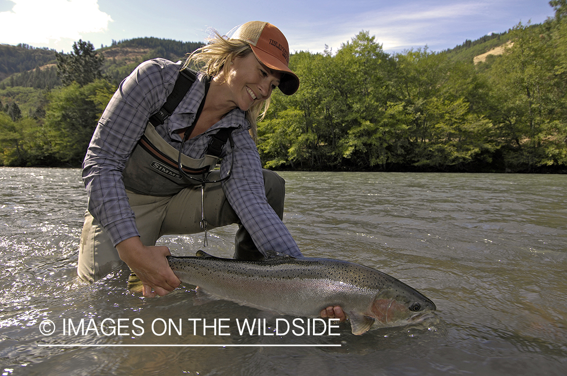 Woman flyfisher with steelhead catch. 