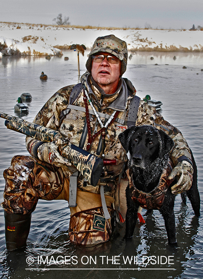 Waterfowl hunter and dog with decoys.