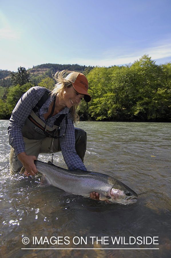 Woman flyfisher with steelhead catch. 