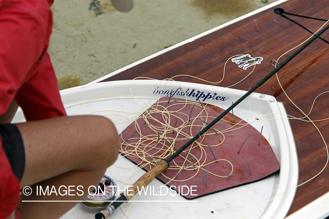 Saltwater flyfishing woman on paddle board tying fly.