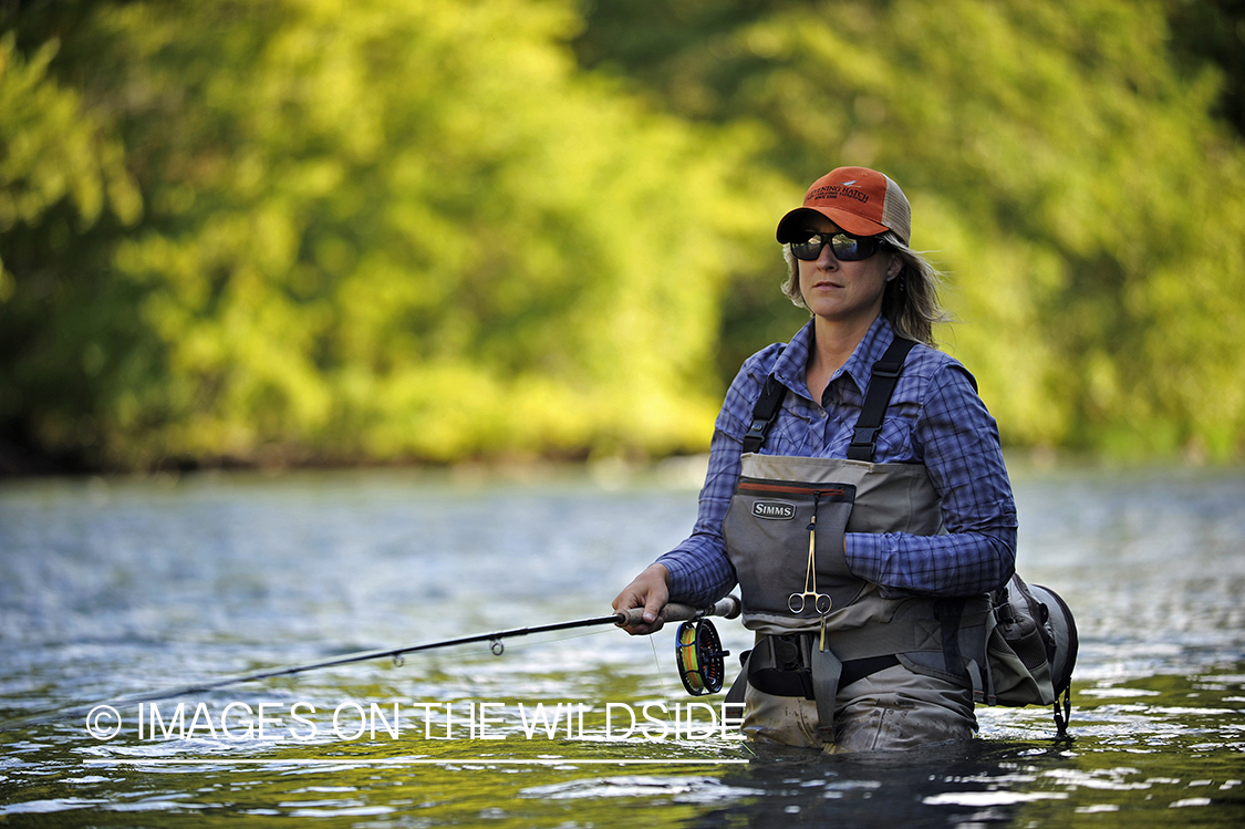 Woman flyfisher casting on river.