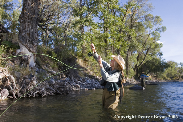 Woman flyfisher undoing a snag on the river.