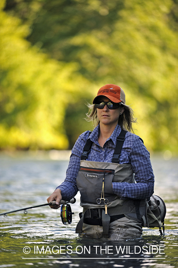 Woman flyfisher casting on river.