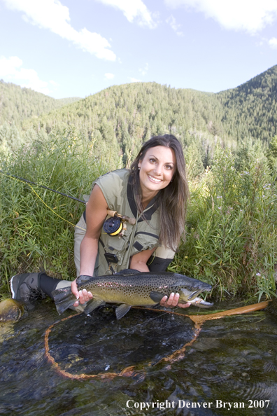 Woman flyfisher with large brown trout.