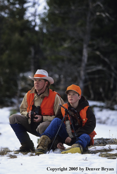 Father and son hunters big game hunting in a field in winter.