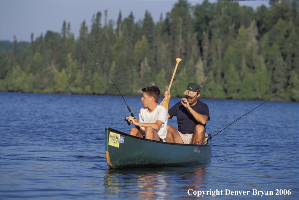 Father and son fishing from cedar canoe.